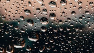 Macro shot of raindrops on a glass window with a colorful blurred background, creating a unique artistic effect.